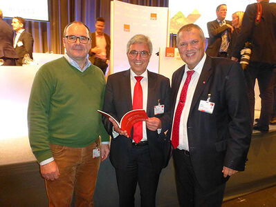 Bernhard Kukatzki (links) und Unterbezirksvorsitzender Martin Wegner (rechts) übergeben das Werk an Roger Lewentz